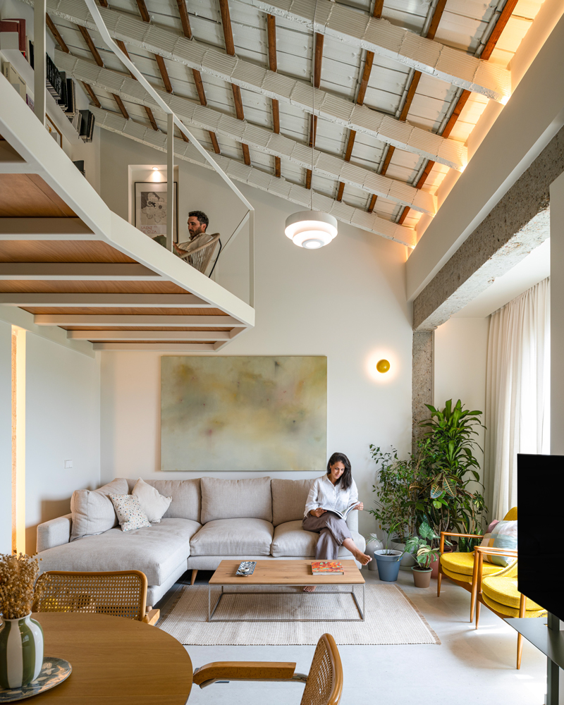 Fotografía de arquitectura interior en Casa Melón, salón con doble altura y pasarela en Murcia Fotografía de arquitectura interior de Casa Melón en Murcia, con salón de doble altura, sofá beige, vegetación y pasarela superior de lectura.