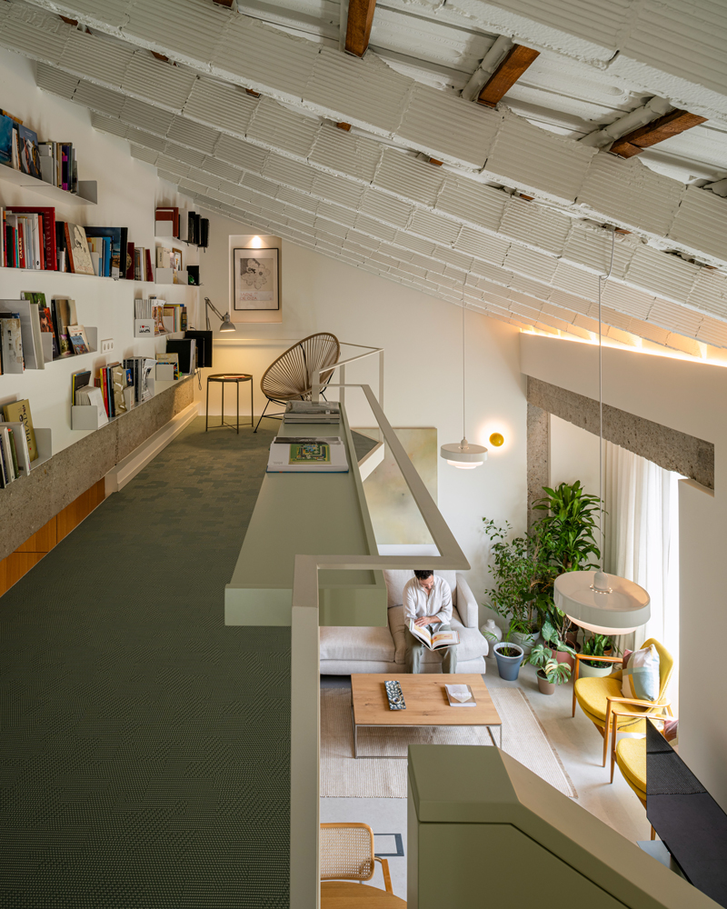 Arquitectura residencial, pasarela flotante y librería abierta en Casa Melón Fotografía de arquitectura interior de la pasarela flotante de Casa Melón, con librería, estanterías y vista al salón desde la planta superior.