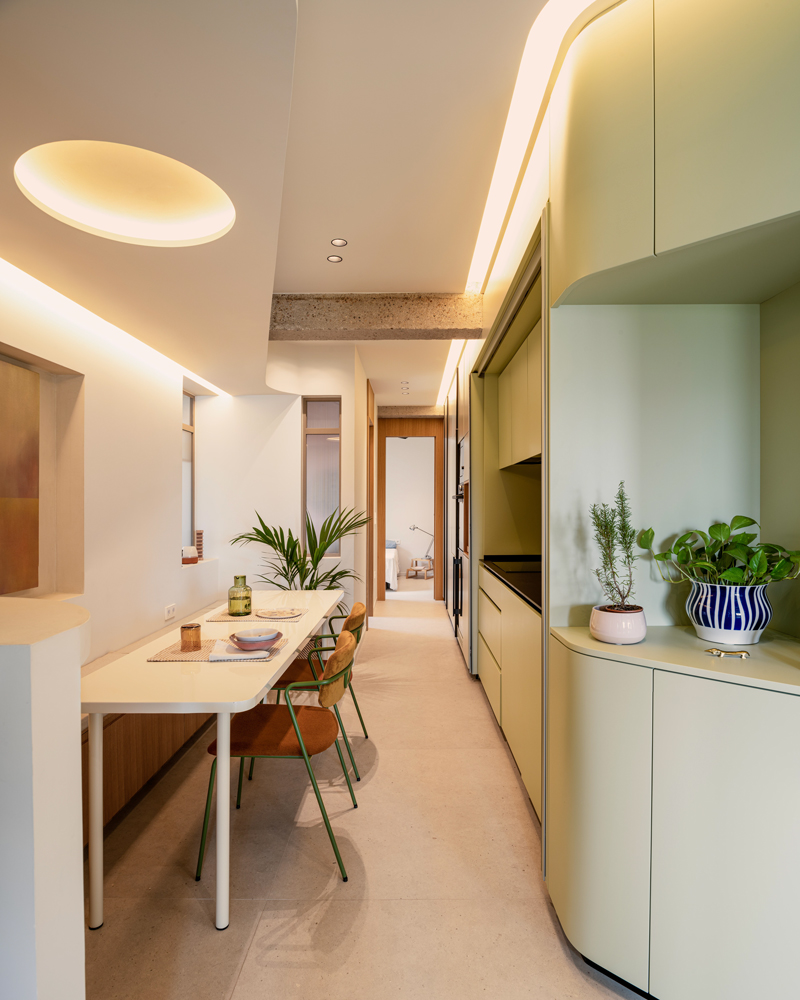 Fotografía de arquitectura interior, cocina lineal iluminada naturalmente en Casa Melón Fotografía de arquitectura interior de la cocina lineal de Casa Melón, con mesa estrecha, sillas de diseño y luz natural desde el patio.