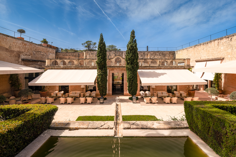 Terraza del patio interior de Cap Rocat, con toldos blancos y una fuente en primer plano